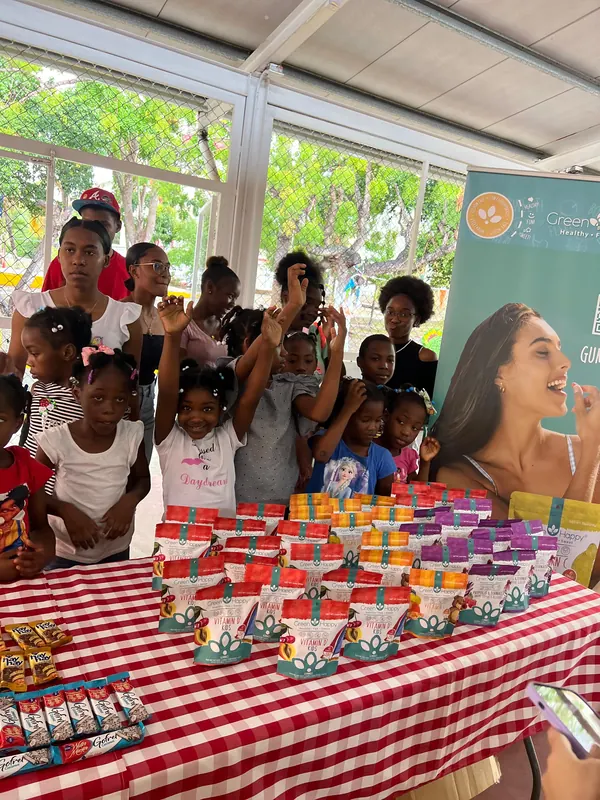 Un grupo de niños posa junto a una mesa de productos aportados por una empresa aliada durante una jornada.