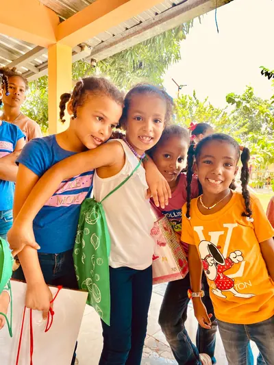 Cuatro niñas se abrazan y sonríen a la cámara con las bolsas que acaban de recibir en una jornada de la fundación.