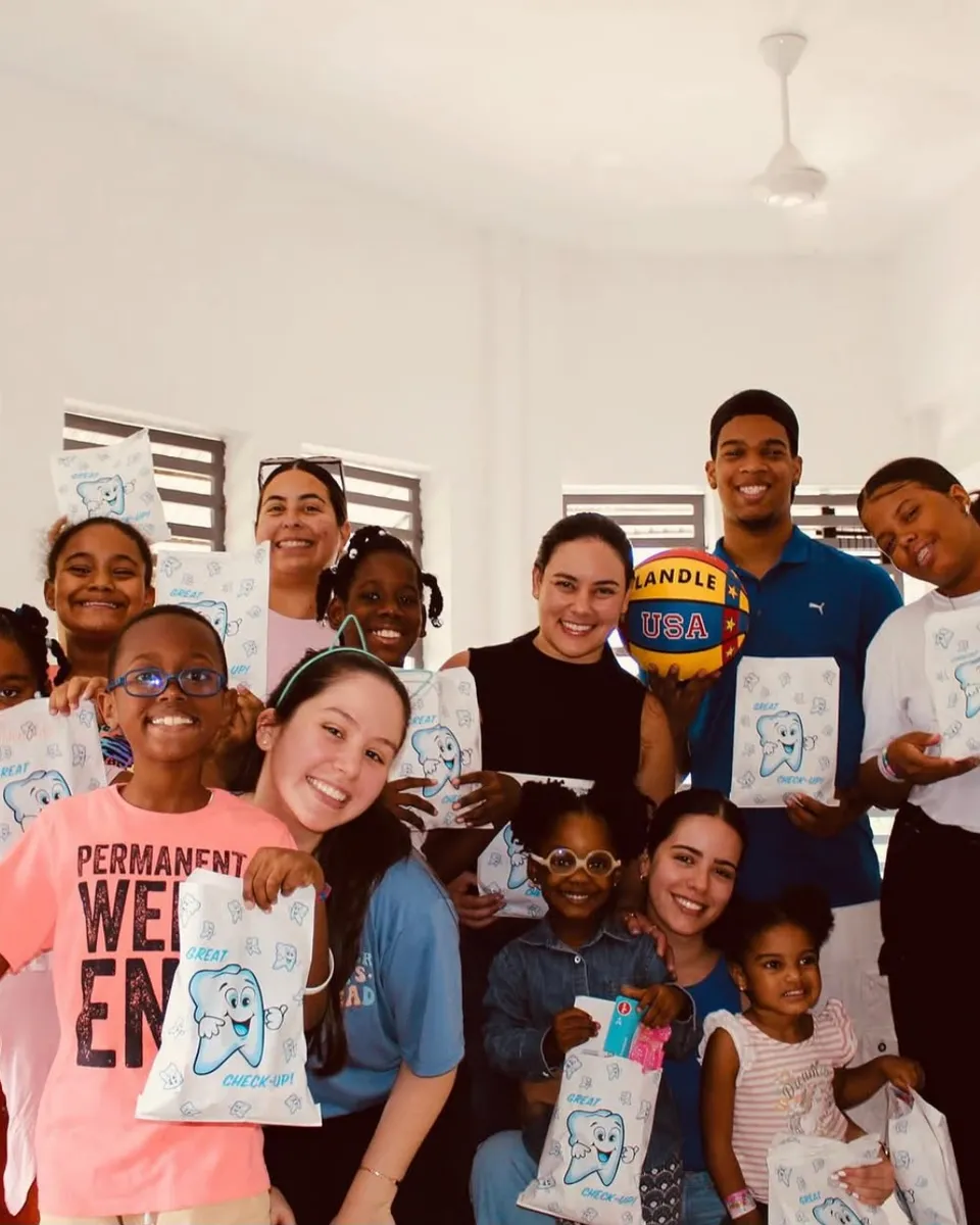 Un grupo de jóvenes voluntarios y niños sonríe a la cámara sosteniendo los kits que acaban de recibir en una jornada de la fundación.