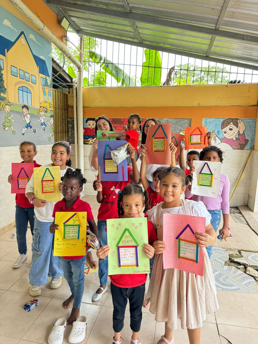 Un grupo de niñas y niños muestra a la cámara las láminas de colores que acaban de elaborar en un taller.